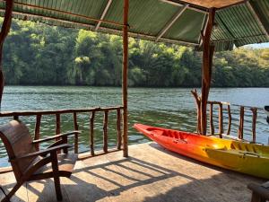 a kayak sitting on a dock next to a chair at แพจิตรธาดาธารน้ำ in Tha Kradan