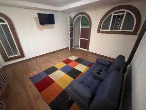 a living room with a blue couch and a colorful rug at Rey 179 in Morelia