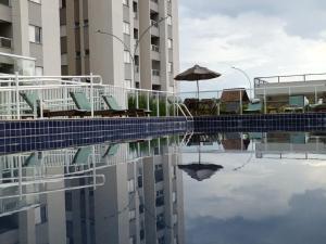 a pool with chairs and an umbrella and a building at Céu da Mantiqueira - Staffy House Extrema in Extrema