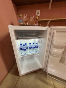 an open refrigerator with bottles of water in it at Quarto próximo ao parque de exposição BR163 in Dourados