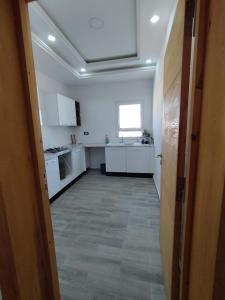 an empty kitchen with white cabinets and a window at Djerba Haven Family in Houmt Souk