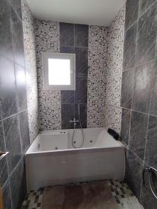 a bathroom with a bath tub and a window at Djerba Haven Family in Houmt Souk