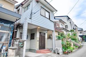 a white house with a door on a street at Tsubaki in Otsu