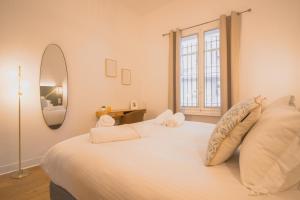 a bedroom with a large white bed with a mirror at Maison Vauban in Marseille