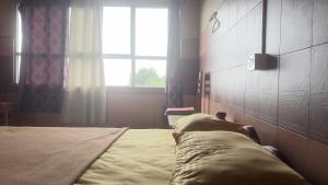 a bedroom with a bed with a window and a window at Vega tourist lodge in Madikeri +9 photos
