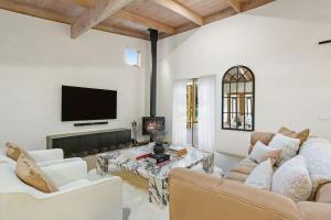 a living room with white furniture and a flat screen tv at Villa Syrene Pool and Spa Retreat in Rye