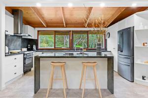 a kitchen with a large island with two bar stools at Villa Syrene Pool and Spa Retreat in Rye