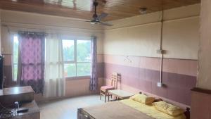 a bedroom with a bed and a table and a window at Vega tourist lodge in Madikeri