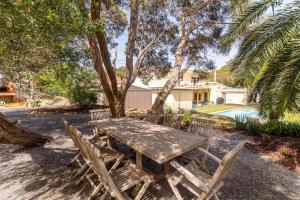 a wooden picnic table and chairs next to a pool at Villa Syrene Pool and Spa Retreat in Rye