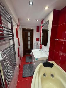 ein rotes Badezimmer mit Badewanne und Waschbecken in der Unterkunft Apcentral in Fălticeni