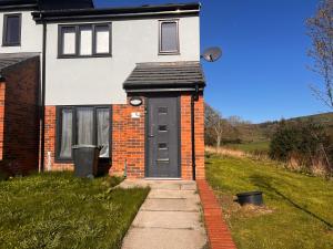 a house with a black door and a sidewalk at Amani Sanctuary 2 Bedroom House in Sherburn Hill