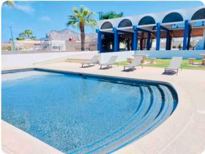 a swimming pool with chairs and a building at Casa Totalmente Equipada en Playa Algodones in San Carlos