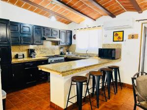 a kitchen with black cabinets and a counter with bar stools at Casa Totalmente Equipada en Playa Algodones in San Carlos