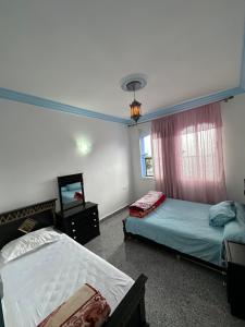 a bedroom with two beds and a mirror and a window at Casa Sharawy in Chefchaouen