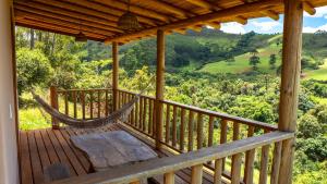 a porch with a hammock and a view of the mountains at Hospedagem Colinas Chalé 2 in Aiuruoca