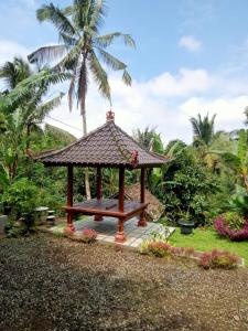 a gazebo in a garden with a palm tree at pondok tegal jero in Jatiluwih