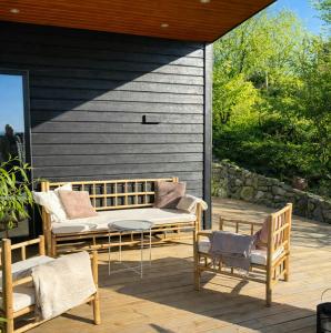 a porch with a bench and chairs on a deck at Summer House On Hillside Plot By Sejerø Bay in Fårevejle