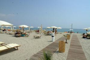 a beach with people sitting on chairs and umbrellas at Residence La Bricola 239 in I Casoni +10 photos