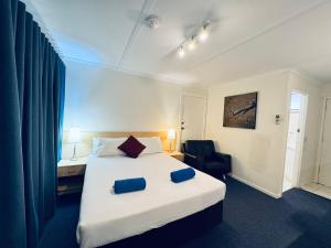 a hotel room with a bed and a chair at Edinburgh Motor Inn in Warragul