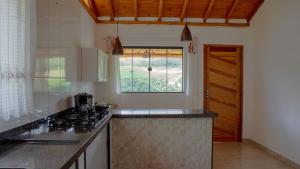 a kitchen with a stove top and a window at Hospedagem Colinas Chalé 2 in Aiuruoca