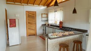 a kitchen with a counter with stools in it at Hospedagem Colinas Chalé 2 in Aiuruoca +34 photos