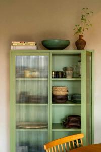 a green cabinet with plates and bowls on it at Restored House With Art In Österlen in Borrby