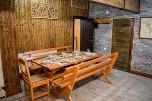 a wooden table with two wooden chairs and a tableablish at Casa Vanatorului Buzaiel in Vama Buzăului
