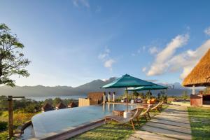 a pool at a resort with chairs and an umbrella at Kintamani Breeze in Kubupenlokan