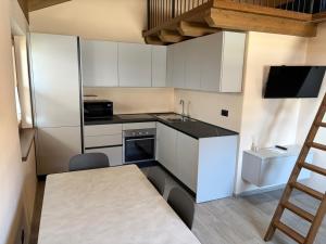 a kitchen with white cabinets and a table and a ladder at Coudrey 2 in Doues