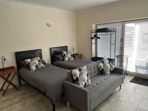two beds in a room with a couch and a window at Sharpley Hall Garden Studio not far from Seaham Beach offering Quiet Private Stay with Secure Parking in Seaham