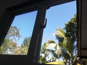 an open window with a view of a palm tree at Meegoda Villa in Kalutara