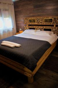a large bed in a bedroom with a wooden headboard at Casa Vanatorului Buzaiel in Vama Buzăului