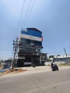a building on the side of a street with a person on a motorcycle at Royal Inn in Mysore