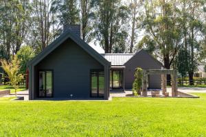 a black house with a green lawn at The Mist, Luxury Farm w Fireplace & Hot tub in Exeter