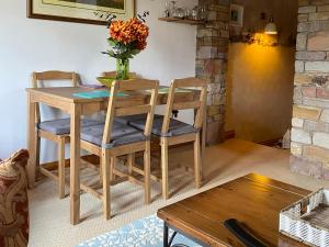 a wooden table with four chairs and a vase with flowers at Swaledale Watch Garden Annexe in Wigton