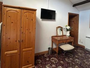 a bedroom with a wooden cabinet and a desk with a mirror at Swaledale Watch Garden Annexe in Wigton