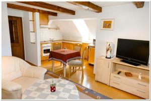 a living room with a tv and a table and a kitchen at Pension Teichschänke in Zwönitz