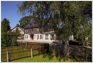 a white house with a fence and a tree at Pension Teichschänke in Zwönitz