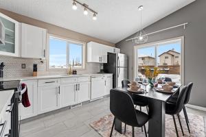 a kitchen with white cabinets and a table with chairs at 5BR Wild Rose- Meadows, AC, Garage, Sleeps 12 in Edmonton