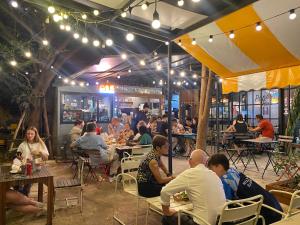 a group of people sitting at tables in a restaurant at The Yard Bangkok Hostel in Bangkok