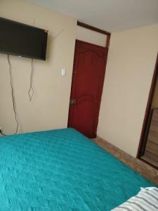 a room with a bed and a red door at Acogedora habitación in Trujillo