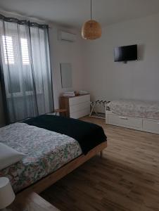 a bedroom with two beds and a flat screen tv at APPARTAMENTO JLENIA in Cisterna di Latina