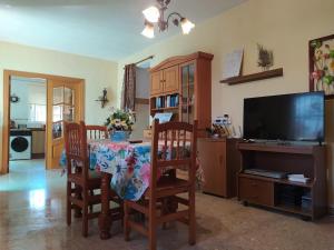 a dining room with a table and chairs and a television at La caseta del llorer in Catadau