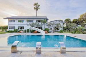 a swimming pool with a slide in front of a house at The Princess Beachfront Resort in Ban Tha Fat