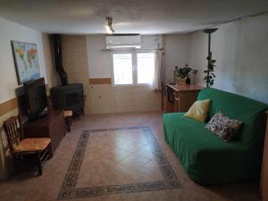 a living room with a green couch and a television at La caseta del llorer in Catadau