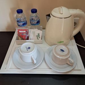 a tray with two cups and a tea pot and water at Grand Pujon View in Songgoriti