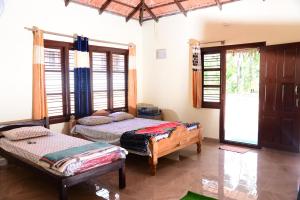 a bedroom with two beds in a room with windows at BlueMoon Homestay - Near to Falls and View Points, Home Food & Estate in Sakleshpur
