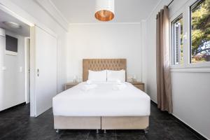 a bedroom with a white bed and a window at Athenean Sea Breeze in Vari