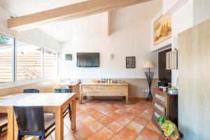 ein Wohnzimmer mit einem Tisch und einem Fernseher in der Unterkunft Hôtel Les Calanques in Les Issambres