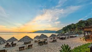 a beach with chairs and straw umbrellas and the ocean at BuBu Villa in Perhentian Islands